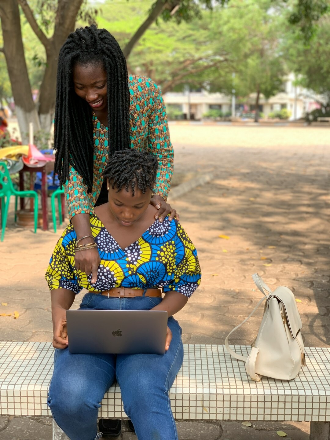 Senior woman learning to use a laptop with help from a young volunteer